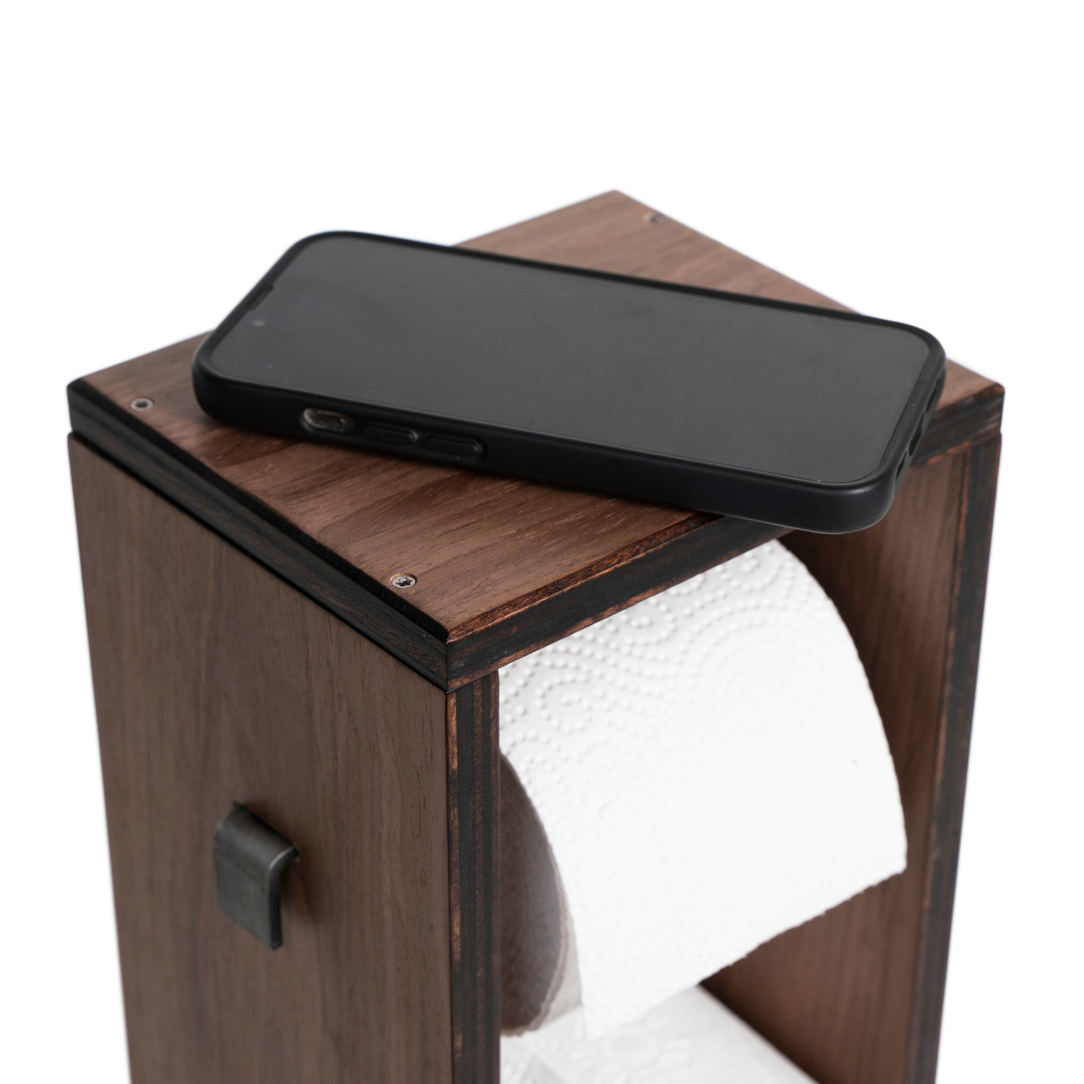 Close-up of a dark walnut veneer toilet roll storage unit, featuring a sleek, flat top with a smartphone placed on it. The design includes an accessible toilet paper roll mounted in an open, minimalist structure.