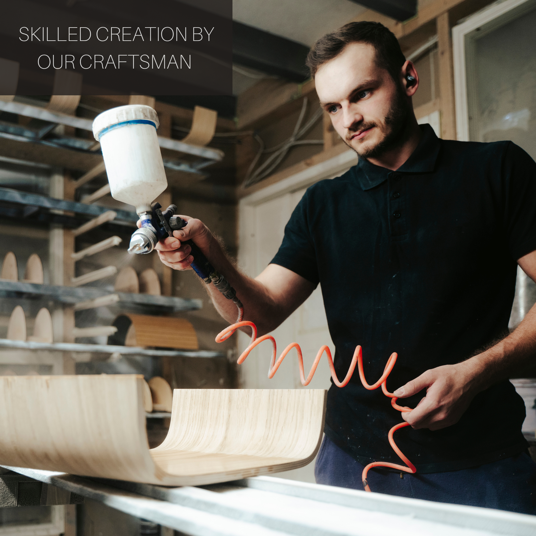 Craftsman using a spray gun in a workshop for wooden interior items