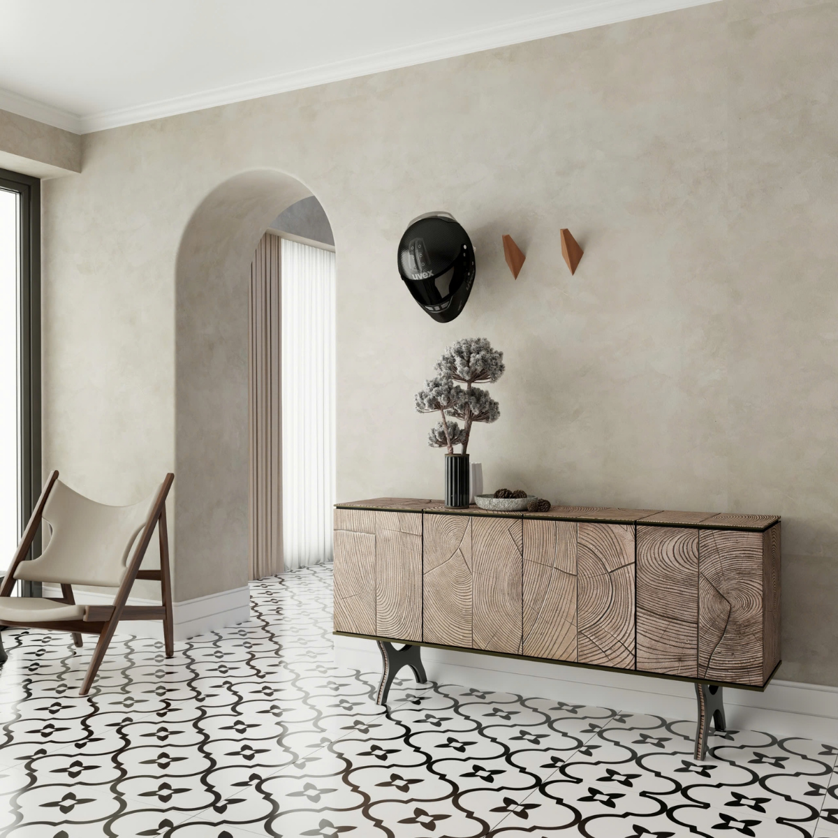 Room with patterned tile flooring, a wooden sideboard, triangular wall hooks holding a black motorcycle helmet, and neutral walls with an arched detail.