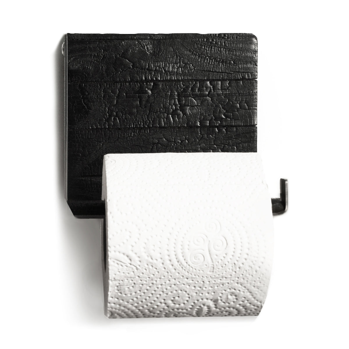 Close-up of a wall-mounted toilet paper holder featuring burned wood with a textured finish and a sleek metal bar holding a roll of toilet paper.