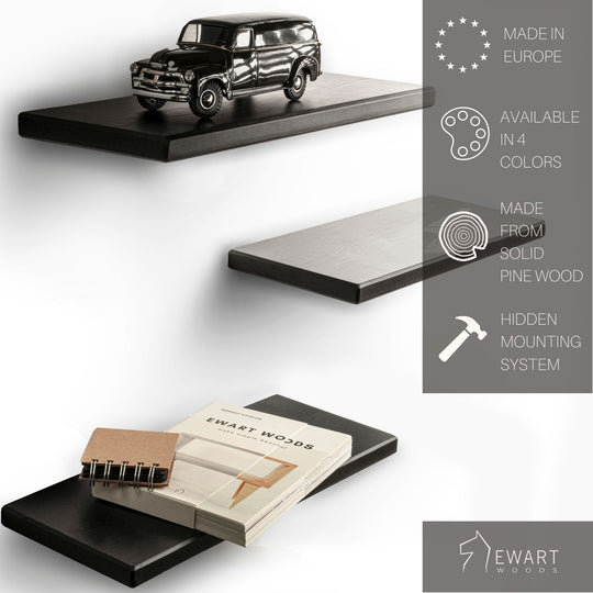 Set of three floating shelves made from solid pine wood, painted black with smooth edges and a hidden mounting system. The top shelf holds a vintage car model, and the bottom shelf displays a notebook and a book titled &