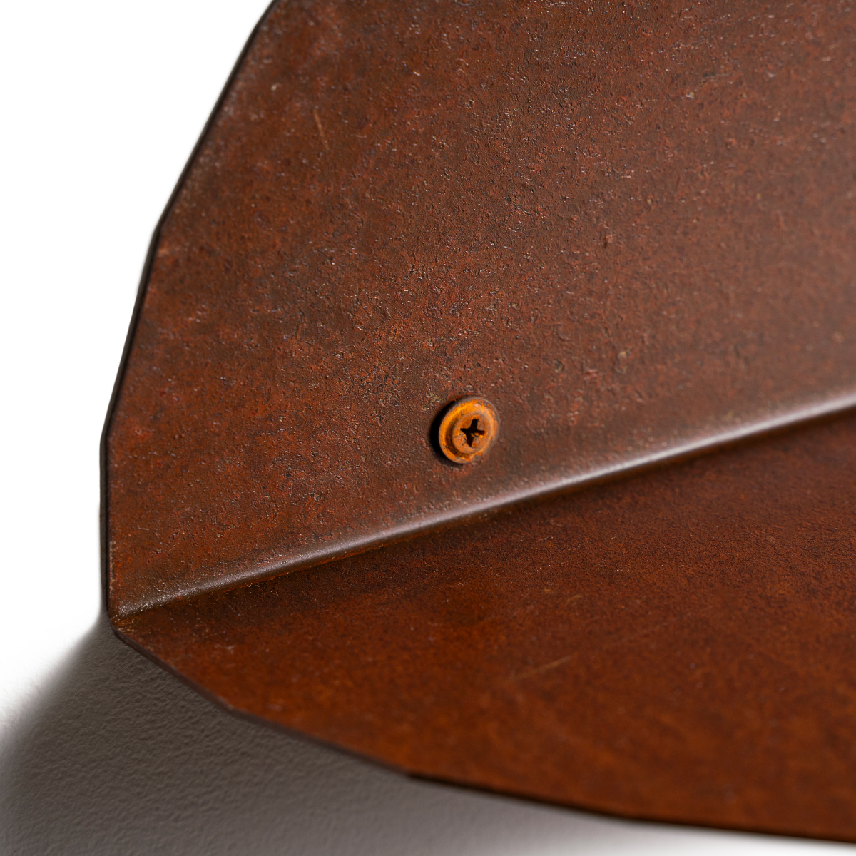 Close-up view of a rusted metal wall shelf highlighting its textured surface and screw detail, showcasing its industrial aesthetic and sturdy construction.