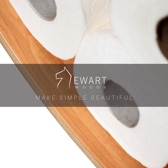 Close-up of a cherry wood curved toilet paper holder, displaying several rolls of toilet paper. The EWART WOODS logo and the slogan MAKE SIMPLE BEAUTIFUL are overlaid on the image.