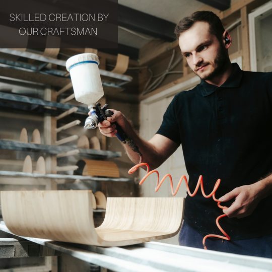 Craftsman using a spray gun in a workshop with wooden furniture