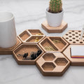 Hexagonal wooden desk organizers arranged on a marble surface, holding paper clips, binder clips, sticky notes, a mug, and a small potted cactus.
