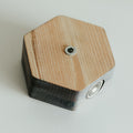 Close-up of the back of a hexagonal grey key holder, showing a metal screw and mounting hardware, with visible natural wood grain patterns.