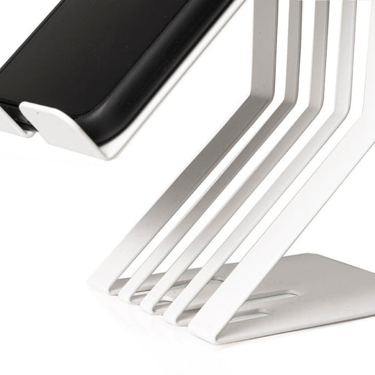 Close-up of a white metal phone holder with a slatted design, emphasizing the modern, minimalist design and integrated charging slot.