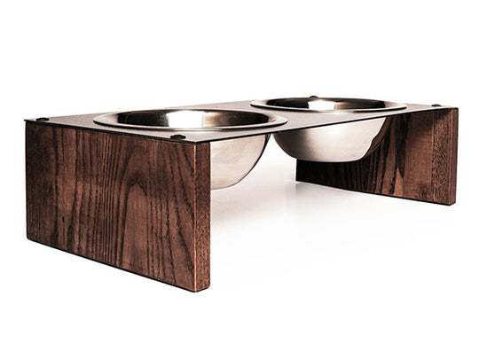 Elevated dog bowl stand with two stainless steel bowls set in a metal top, supported by wooden legs with a rich wood grain texture.