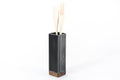 Black metal utensil holder with a wooden base and wooden utensils.