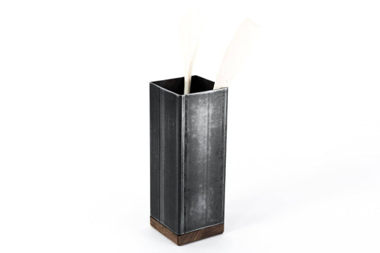 Black metal utensil holder with a wooden base and wooden utensils.