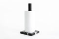 Paper towel holder featuring a black marble base with white veining and a black metal stand, holding a white paper towel roll, designed for a sleek and contemporary look.