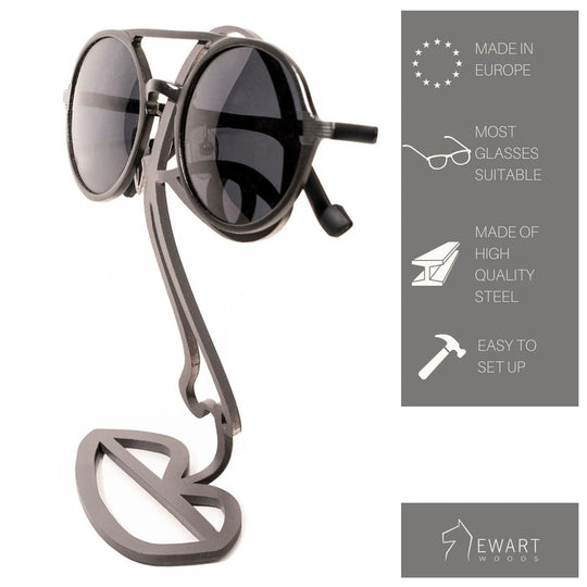 Black steel glasses stand with an abstract face design, holding sunglasses over the eyes. Made in Europe from durable steel, compatible with most glasses, and easy to assemble.