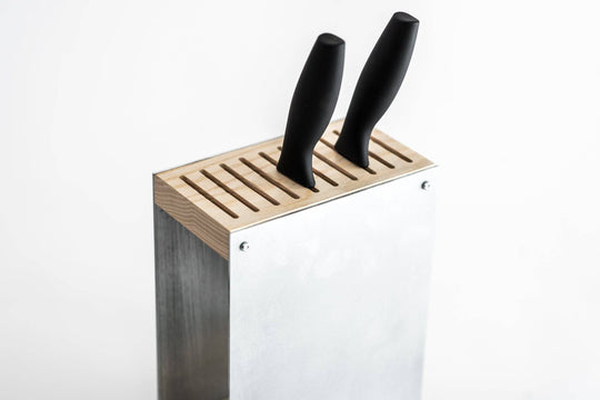 Silver metal knife block with a wooden top, holding two black-handled knives. The block has a sleek design and is displayed against a plain white background.