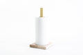 Paper towel holder with a beige marble base and gold metal stand, holding a white paper towel roll, designed for a sleek and sophisticated look.