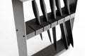 Angled view of a sleek, modern knife block featuring a black metal frame and dark wooden insert, holding six black-handled knives in evenly spaced horizontal slots.