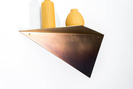 Stylish triangular brushed copper wall shelf, showcasing a minimalist design with two textured yellow vases, adding a modern touch to the decor.