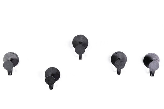 Five black metal hooks with a brushed texture and circular backplates, providing a modern, industrial aesthetic for hanging items.