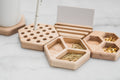 Close-up of hexagonal wooden desk organizers, featuring compartments for paper clips, thumbtacks, a pen holder, and a cardholder. A matching wooden coaster and pen add a touch of elegance to the workspace.