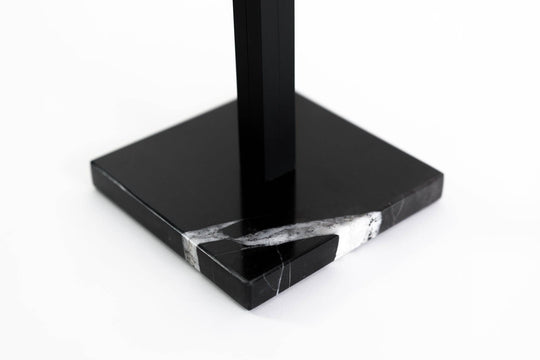 Close-up of a black marble base with striking white veining and a black metal stand, highlighting the luxurious design of the paper towel holder.