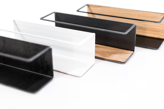 Durable kitchen organizers with white and black metal frames and wooden inserts, designed to hold and display spice jars in a clean, functional style.
