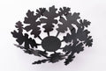 Black metal bowl with intricate oak leaf-shaped cutouts, showcasing a modern and elegant design.