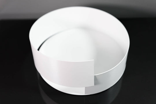 Sleek white metal bowl featuring a minimalist overlapping design, displayed on a glossy black surface for a modern aesthetic.