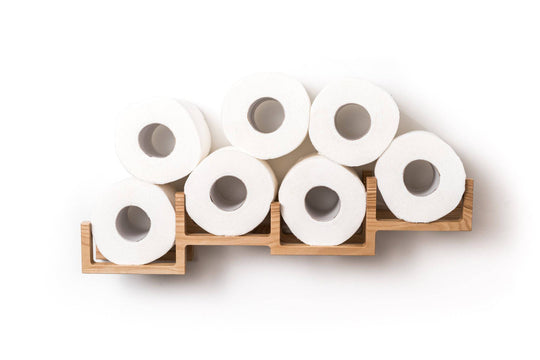 Front view of a wooden wall-mounted toilet paper holder, displaying eight rolls of toilet paper arranged in a unique, stacked design with square frames.