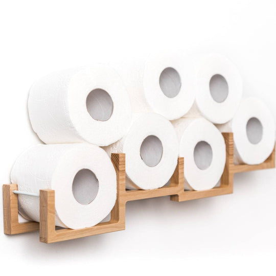 Close-up of a wooden wall-mounted toilet paper holder, displaying eight rolls of toilet paper. The holder has a modern design with square frames.