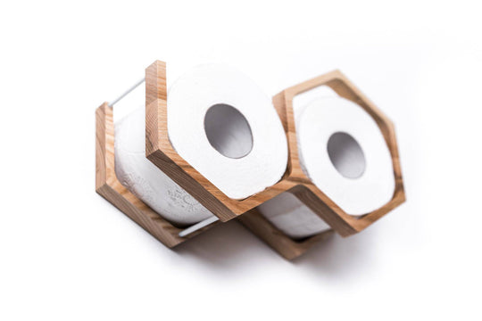 Close-up of a wall-mounted wooden mini honeycomb toilet paper holder, displaying two rolls of toilet paper. The holder features a textured wood surface, highlighting the natural grain in a modern design.