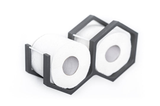 Close-up of a wall-mounted gray mini honeycomb toilet paper holder, displaying two rolls of toilet paper. The holder features a textured wood surface, highlighting the natural grain in a modern design.