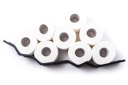 Close-up of a wall-mounted black zigzag toilet paper holder displaying eight rolls of toilet paper stacked in a zigzag pattern.